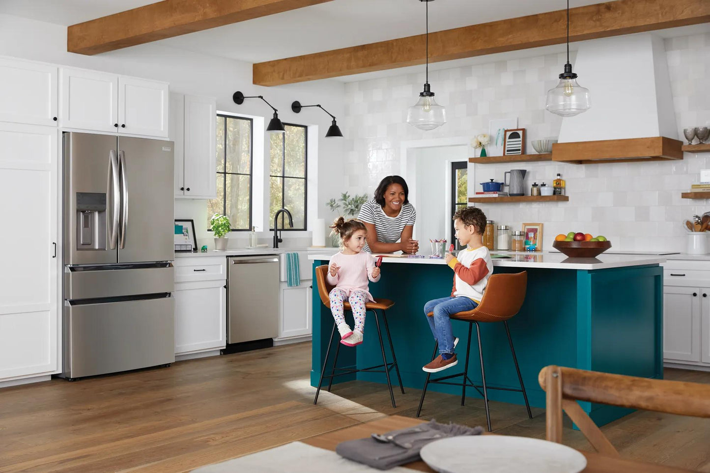 Modern kitchen with stainless steel appliances, white cabinetry, teal island, and family enjoying breakfast together