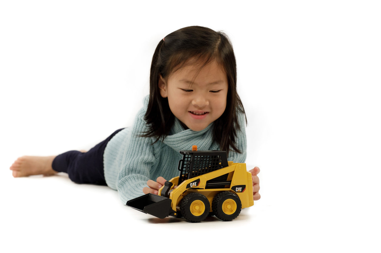 Child playing with a yellow Bruder CAT skid steer loader toy for imaginative construction and home improvement fun
