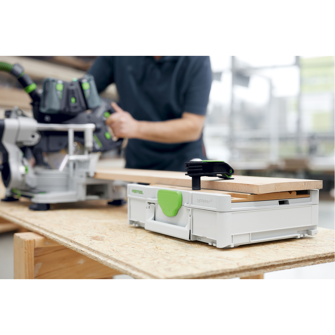 Festool modular work surface with clamped wooden board set on a sturdy table, highlighting tool storage and woodworking precision in a workshop setting.