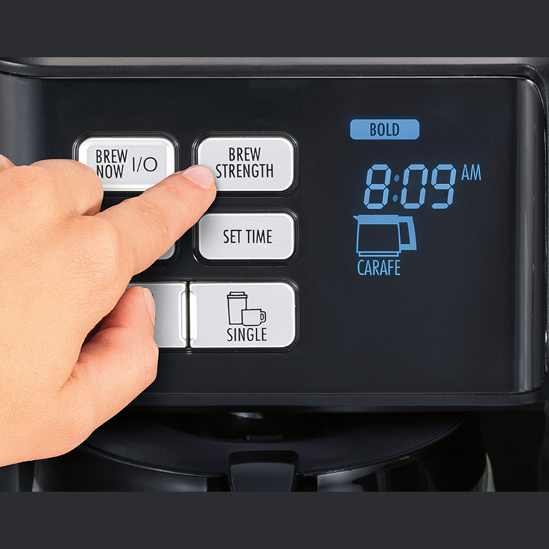 Hand pressing brew strength button on black coffee maker with digital time display in small kitchen appliances collection