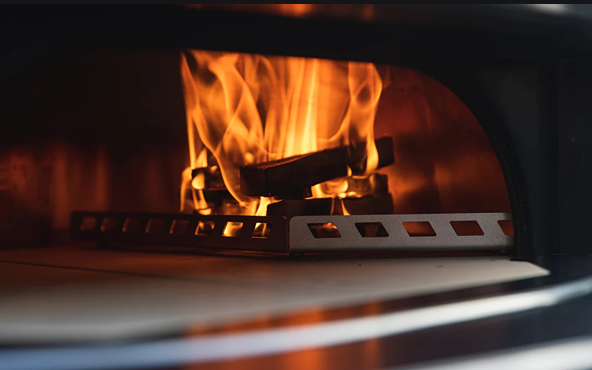 Metal wood rack positioned inside dome oven with burning fire, part of grilling tools and outdoor living collections
