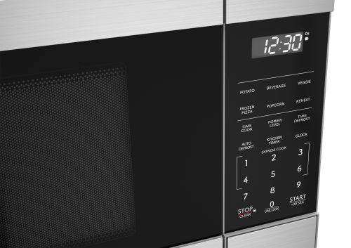 Close-up of stainless steel microwave keypad with digital clock and preset cooking options in kitchen appliances collections