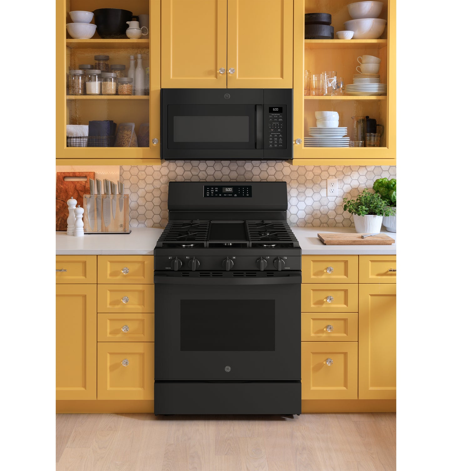 Black free-standing gas range with digital controls and microwave installed above, set within yellow kitchen cabinetry