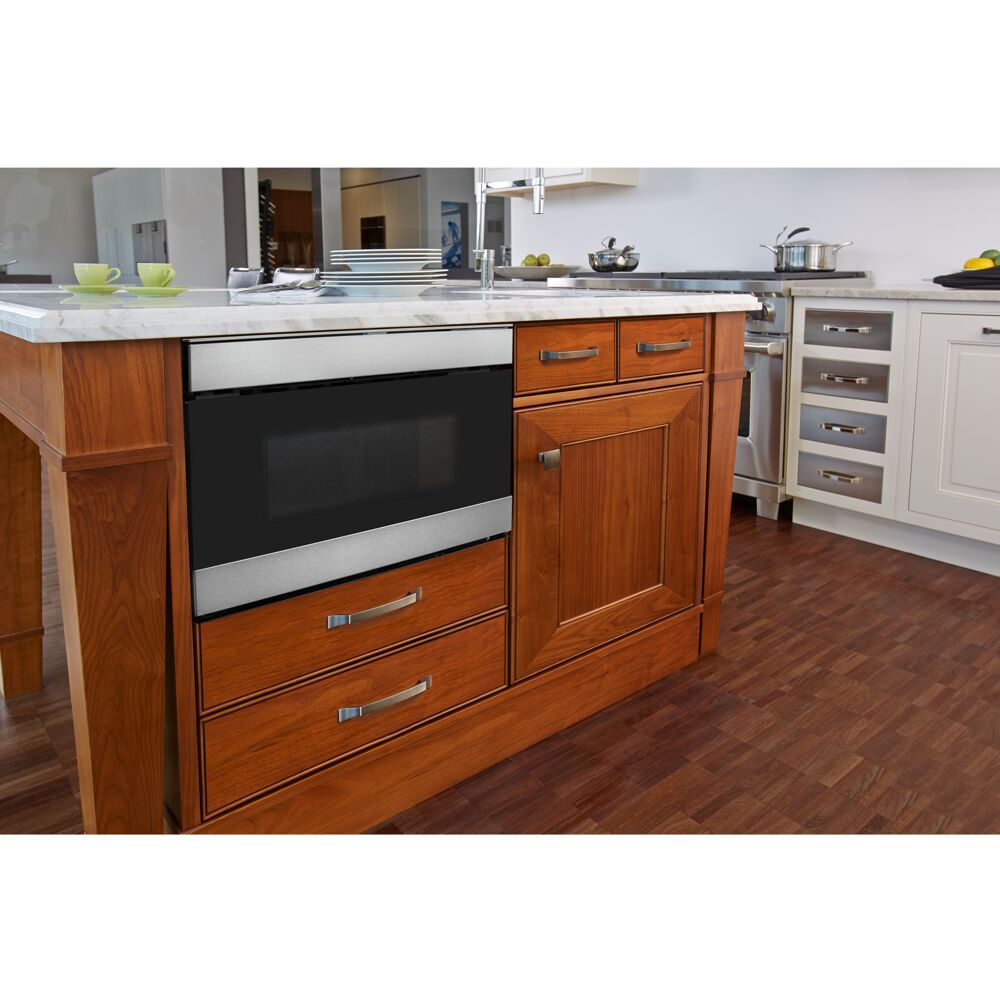 Built-in microwave drawer with stainless steel trim installed in warm wood cabinetry in modern kitchen setting