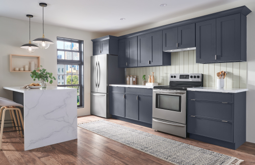 modern kitchen with navy blue cabinetry, stainless steel appliances, white marble island, and hardwood flooring
