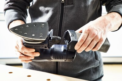 Person holding a cordless delta sander with a triangular sanding pad preparing for a home improvement task