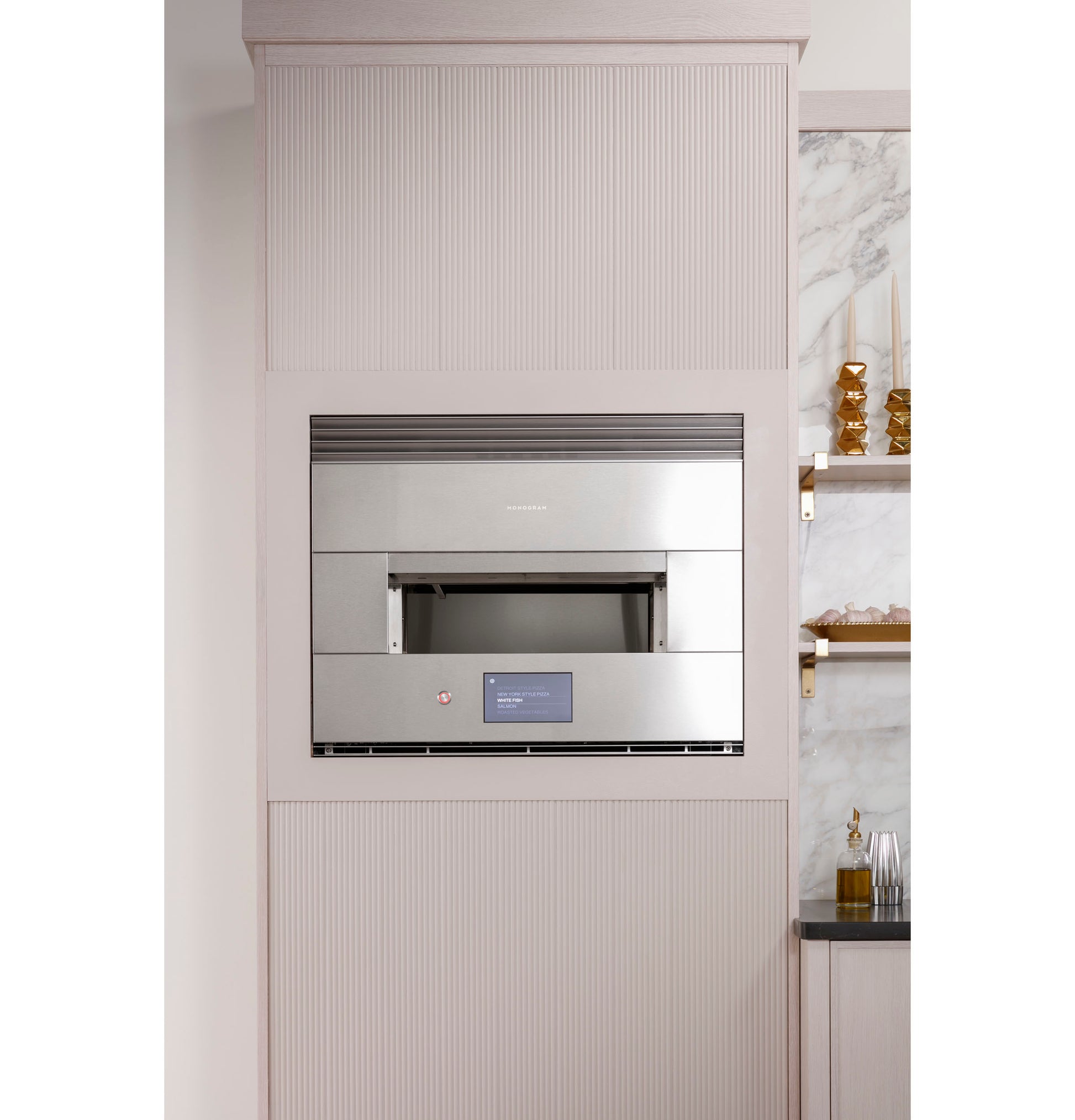 Stainless steel built-in wall oven with digital display, installed in a modern kitchen with marble accents and shelves