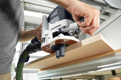 Close-up of person operating a Festool router on a wooden board for precise woodworking and home improvement tasks