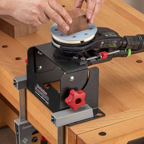 Black metal tilting sander base with red adjustment knob securely clamped to workbench for woodworking tool use