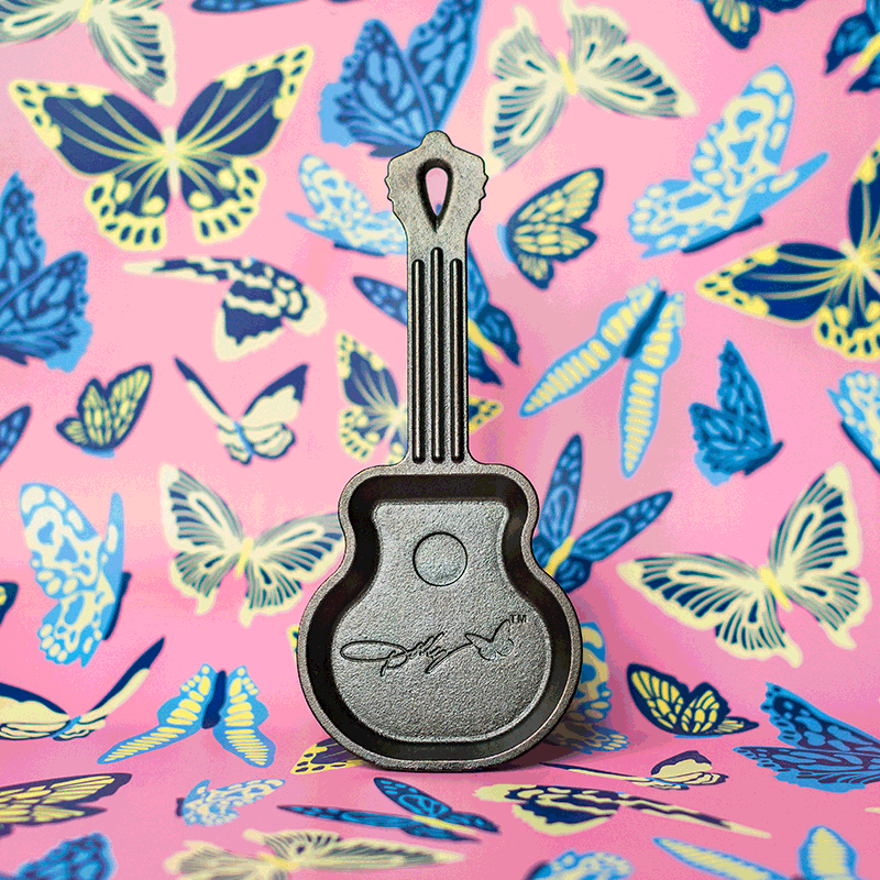 Cast iron mini skillet shaped like a guitar with engraved signature detail against butterfly patterned background