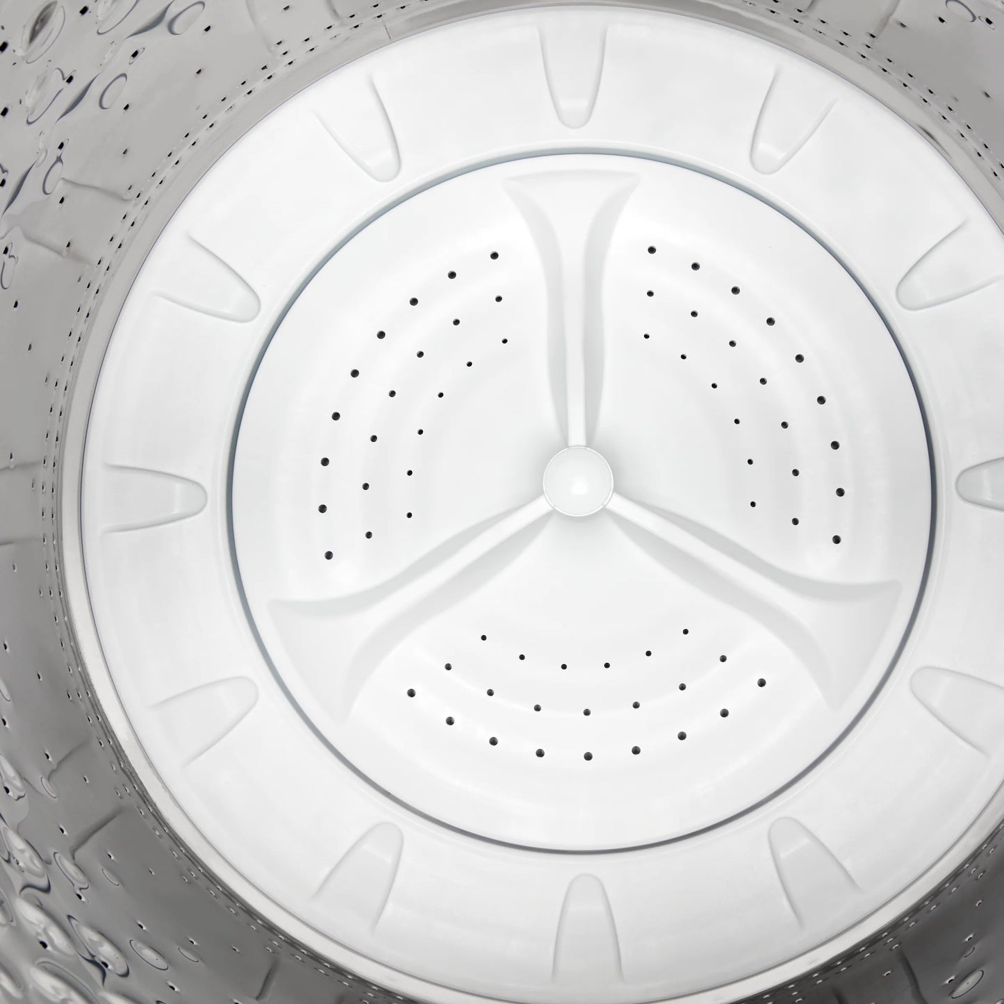 Interior view of a stainless steel washing machine drum with perforated holes and plastic agitator in home appliance collection