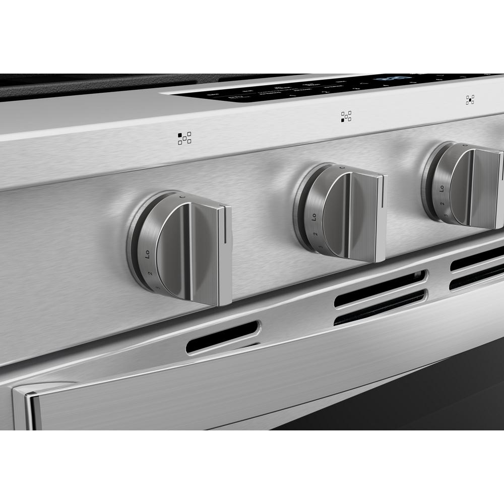 Close-up of stainless steel gas range control knobs with vent slots below, part of modern kitchen appliances collection