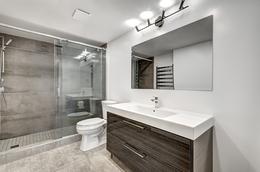 Modern bathroom with glass shower, wall-mounted vanity with sink, large mirror, and toilet for home improvement use