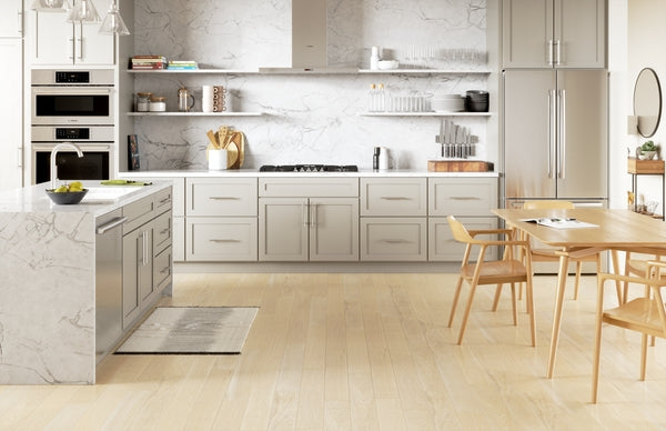 Bright modern kitchen with stainless steel gas cooktop, marble countertops, light wood flooring, and dining area seating