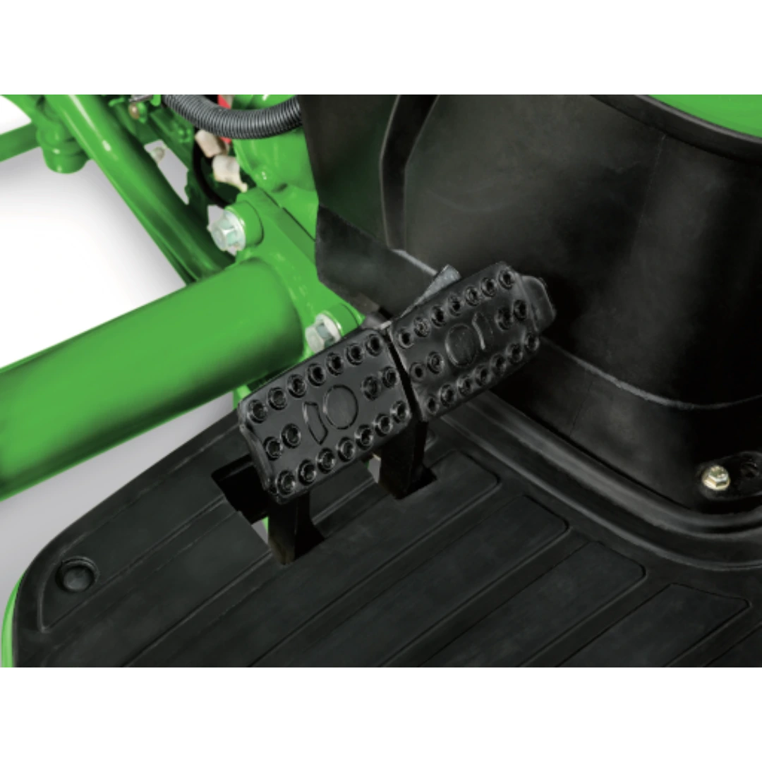 Close-up of black metal foot pedals and textured rubber floor mat in operator station of a John Deere 4044R Compact Tractor, featured in Outdoor Power Equipment at Hartville Hardware.