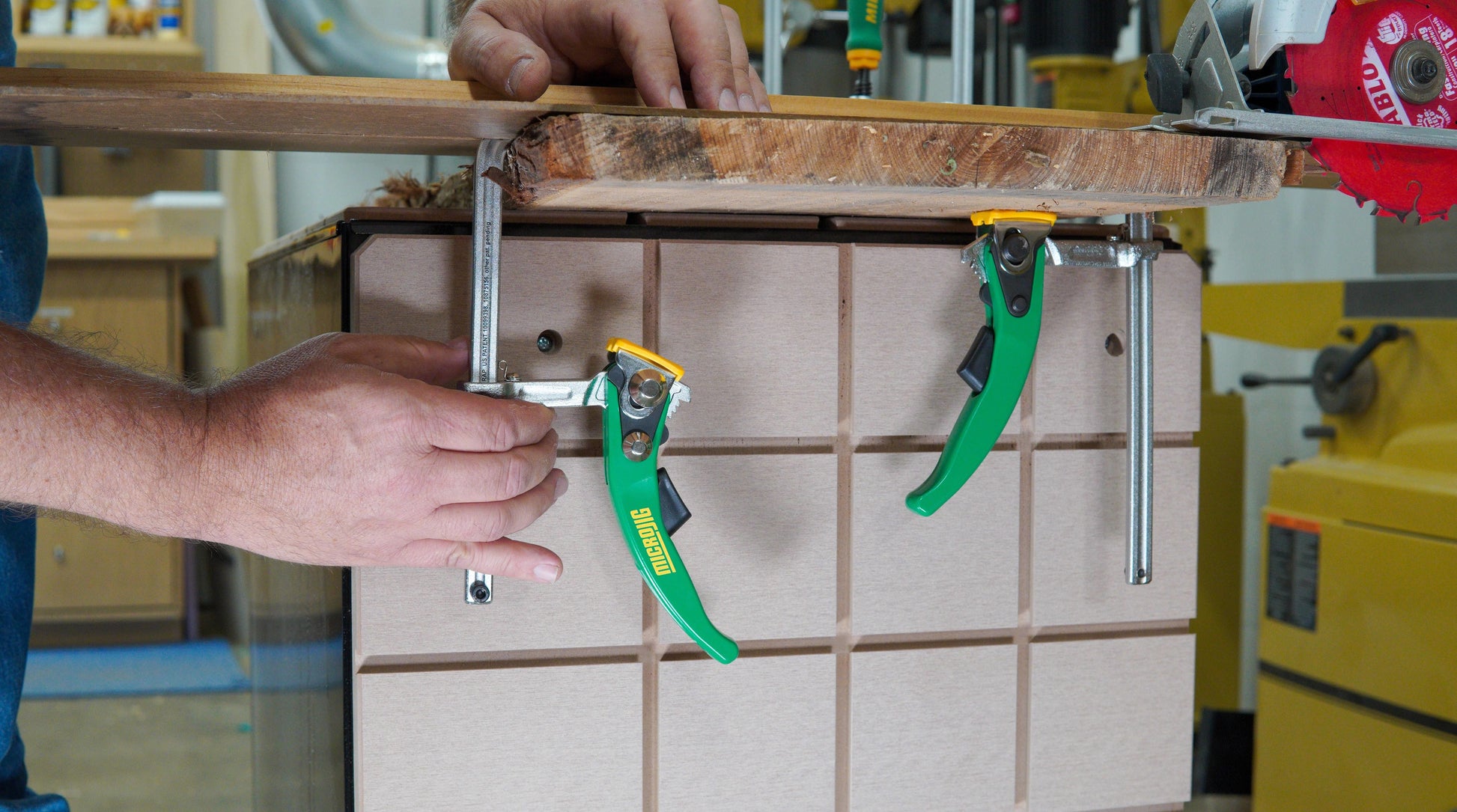 Two green-handled ratchet clamps securing a wooden board on a workbench for woodworking and home improvement tasks