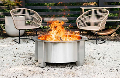 Outdoor stainless steel smokeless fire pit with bright flames surrounded by patio furniture for outdoor living space