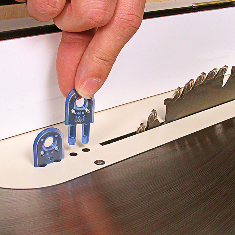 Hand adjusting blue plastic splitter parts near circular saw blade on a table saw for woodworking tools and home improvement