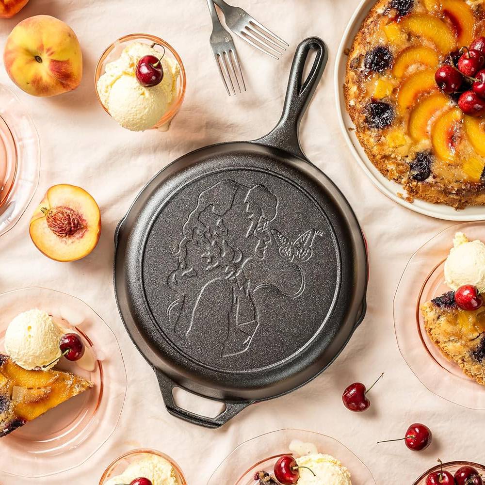 Cast iron skillet with embossed profile and butterfly, surrounded by peach dessert and ice cream, part of Kitchenware collection