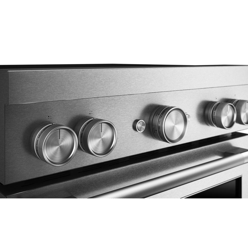 Brushed stainless steel control panel with five round commercial-style knobs on induction range in appliances collection