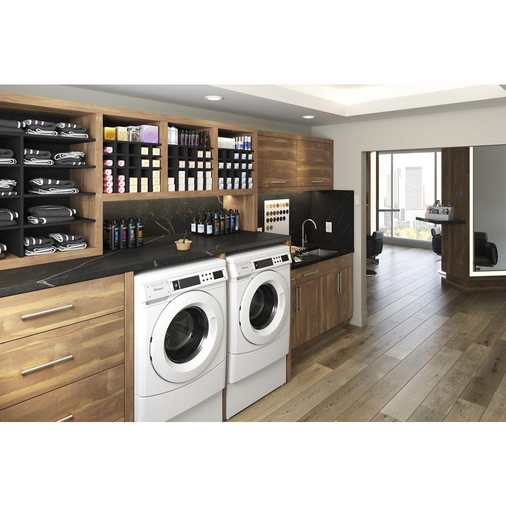 Commercial front-load washers installed in wood cabinetry with black countertop and organized shelves in modern laundry space