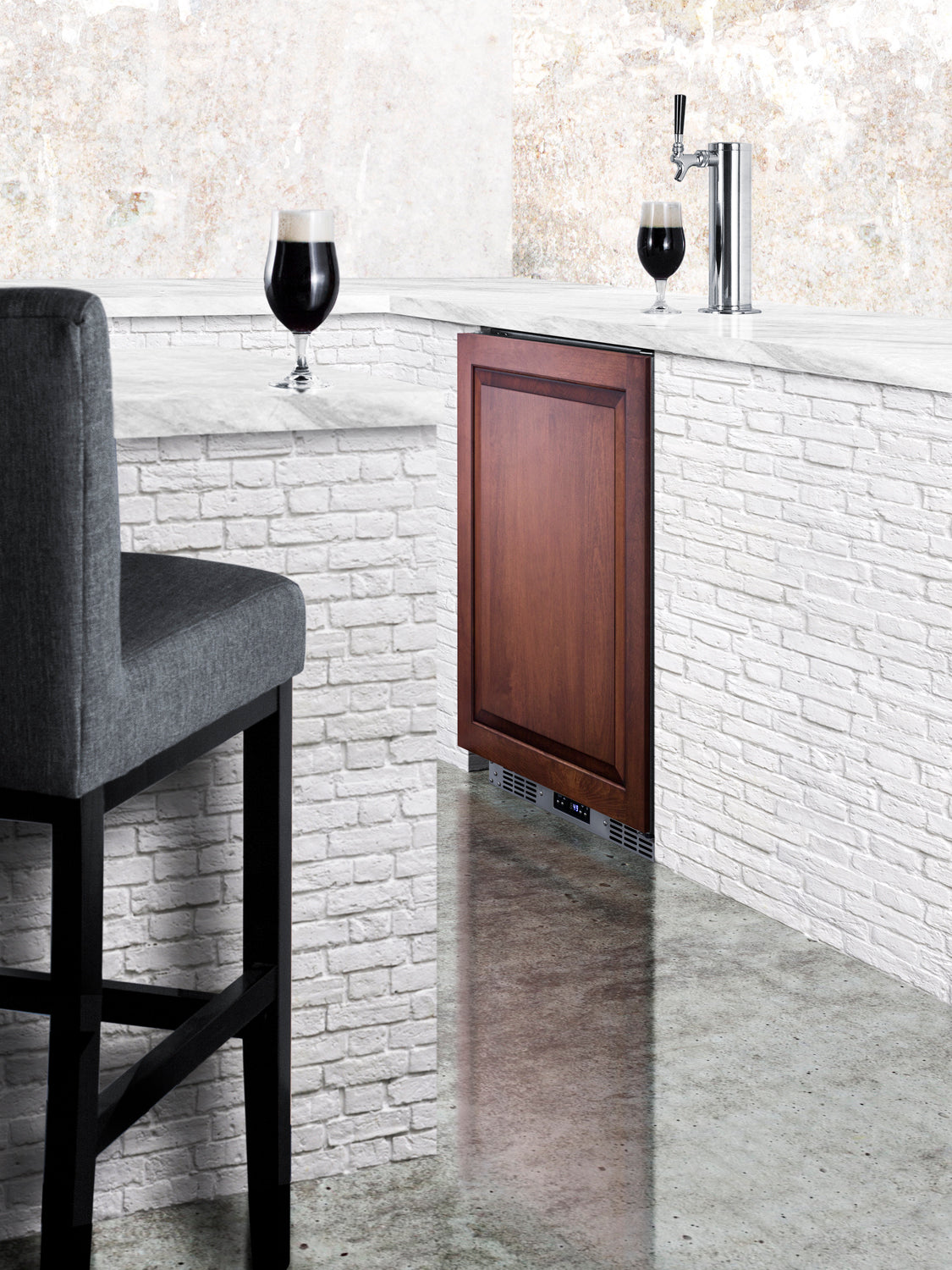 Built-in beverage cooler with wooden panel door, stainless steel draft tower, and dark beer pour on modern bar counter