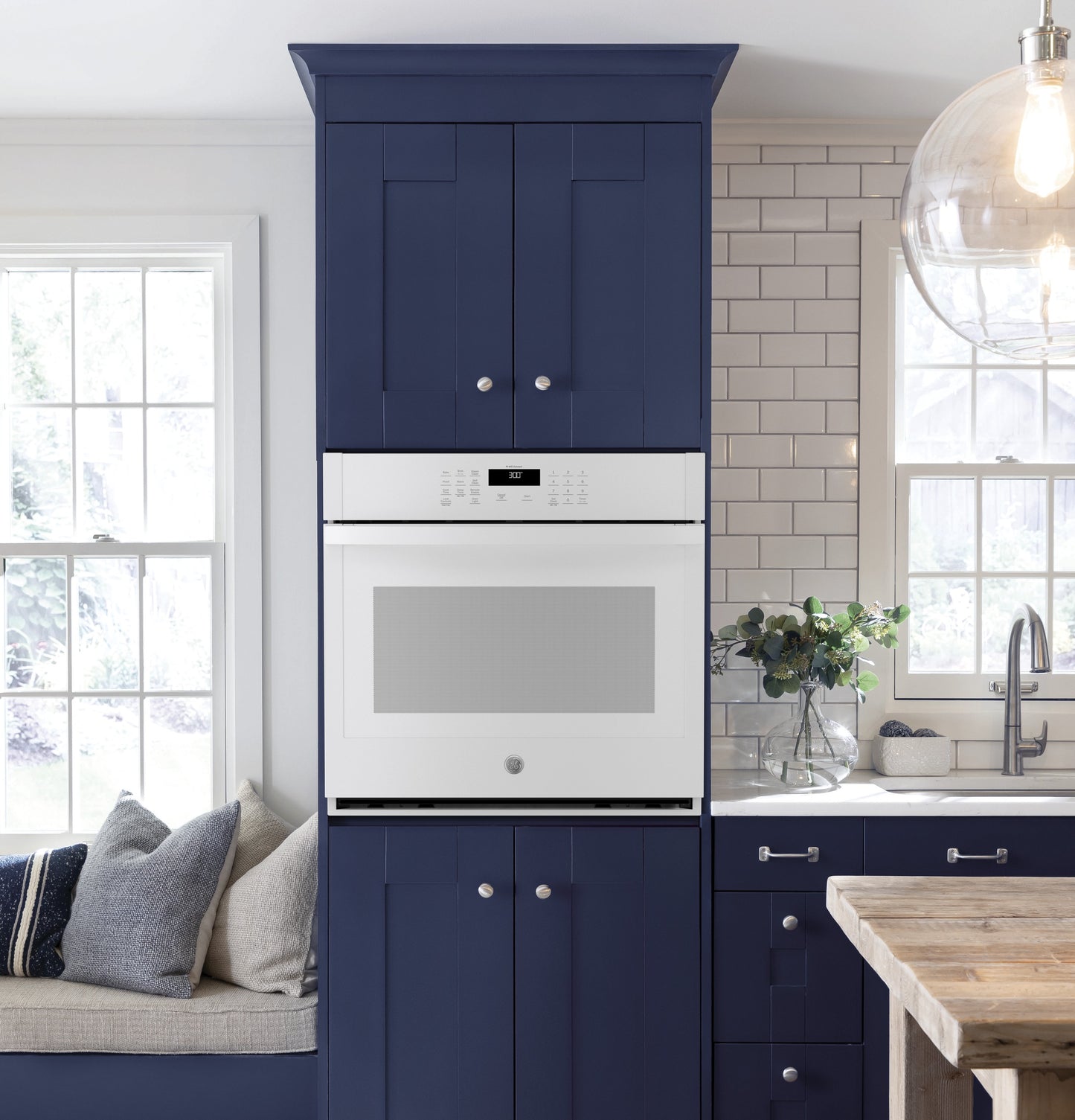 Built-in white single wall oven integrated into navy blue kitchen cabinetry in modern kitchen and appliances collection