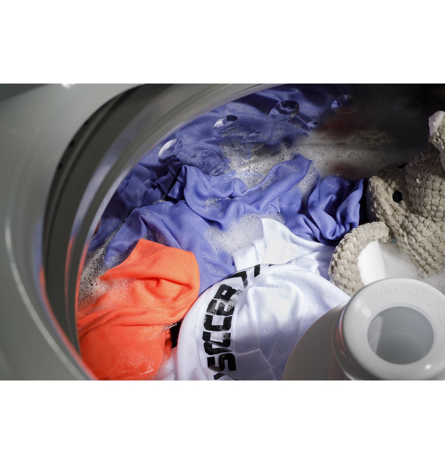 Open top load washer filled with colorful clothes and soap suds during wash cycle from Washers & Dryers collection