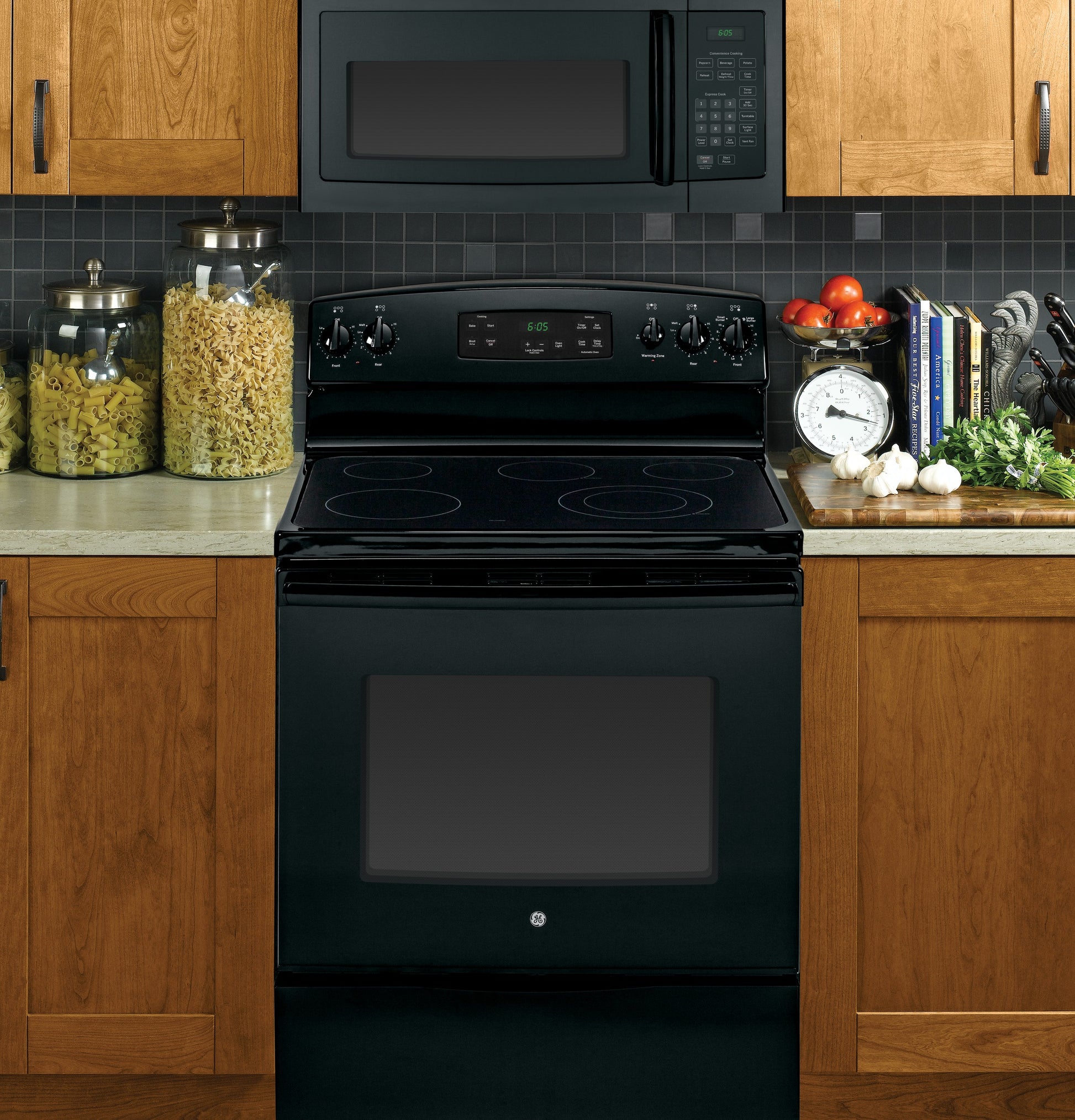 Black over-the-range microwave and electric stove with digital controls in a kitchen with wooden cabinets and counter decor