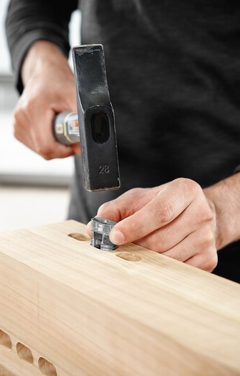 Person installing a Festool Domino Connector split anchor into a wooden board using a hammer tool accessory
