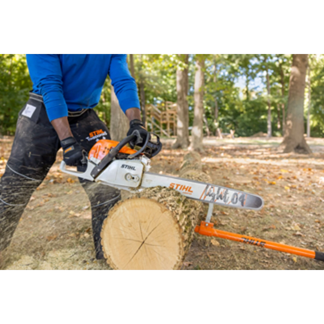 Person wearing gloves and using an orange and white chainsaw to cut a large log outdoors in a wooded area