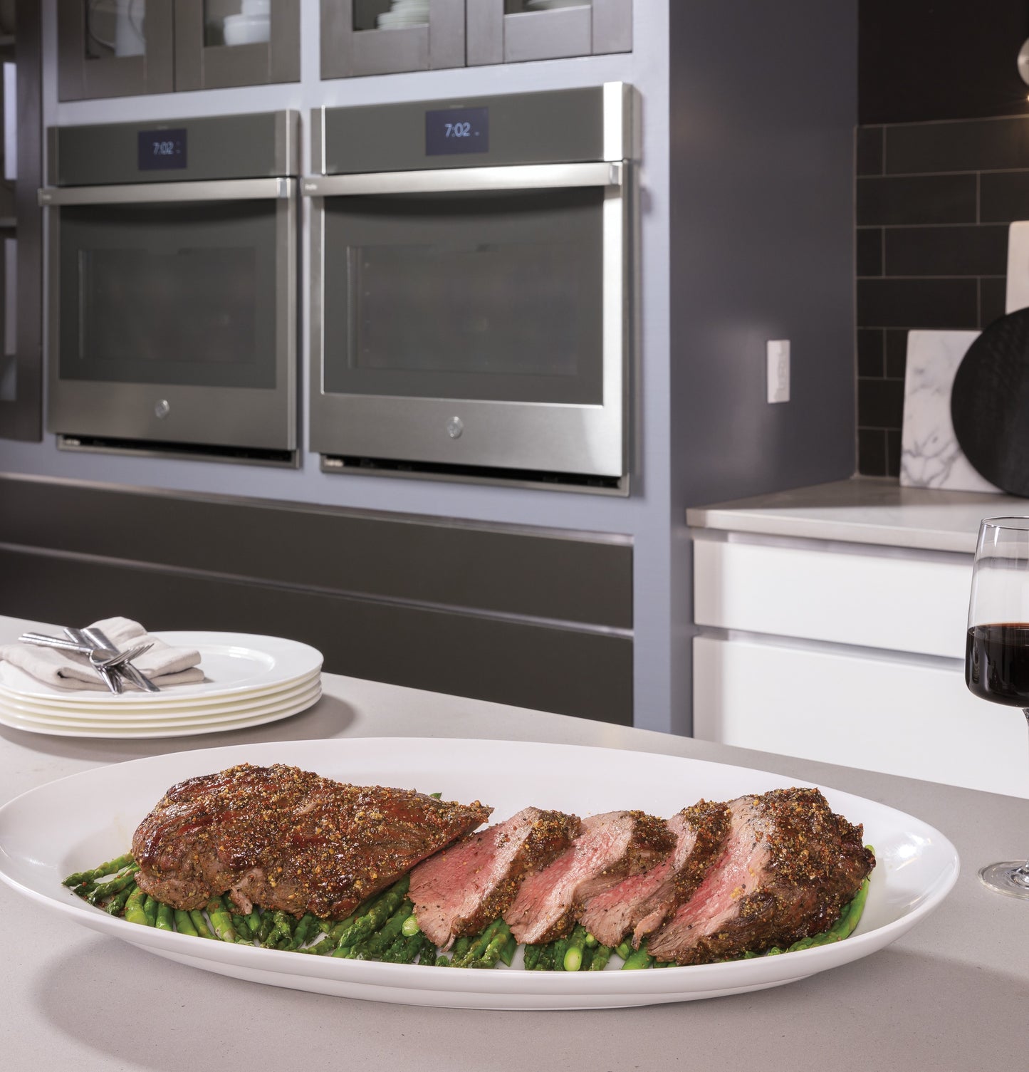 Plated sliced roast with asparagus on kitchen island in front of stainless steel built-in convection double wall ovens