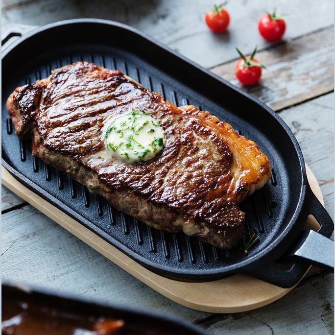 Premium cast iron grizzler pan with removable handle cooking steak, part of grilling tools and outdoor living collections