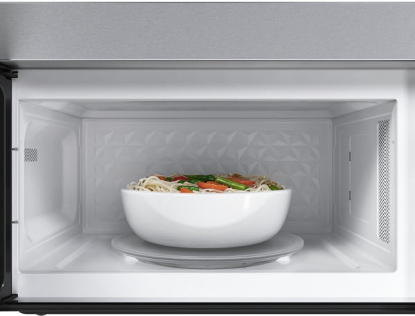 Interior view of stainless steel over-the-range microwave with white bowl of vegetables and noodles inside