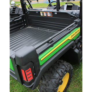 Close-up of trailer bed and rear tail light on green John Deere utility vehicle with rugged tires outdoors