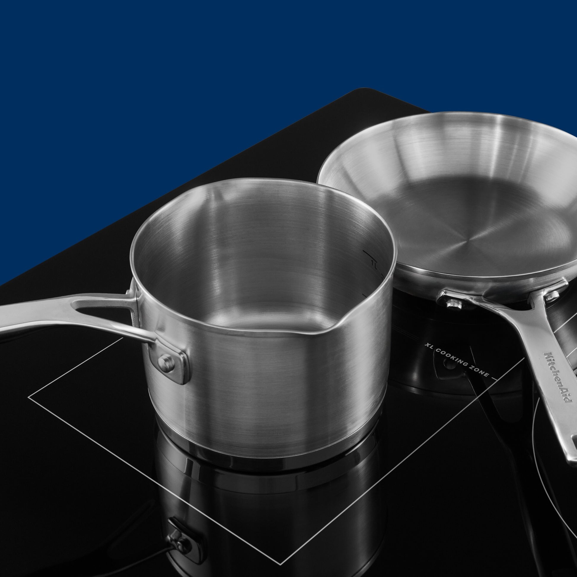 Stainless steel saucepan and skillet sitting on black induction cooktop with XL cooking zone in kitchen appliances collection