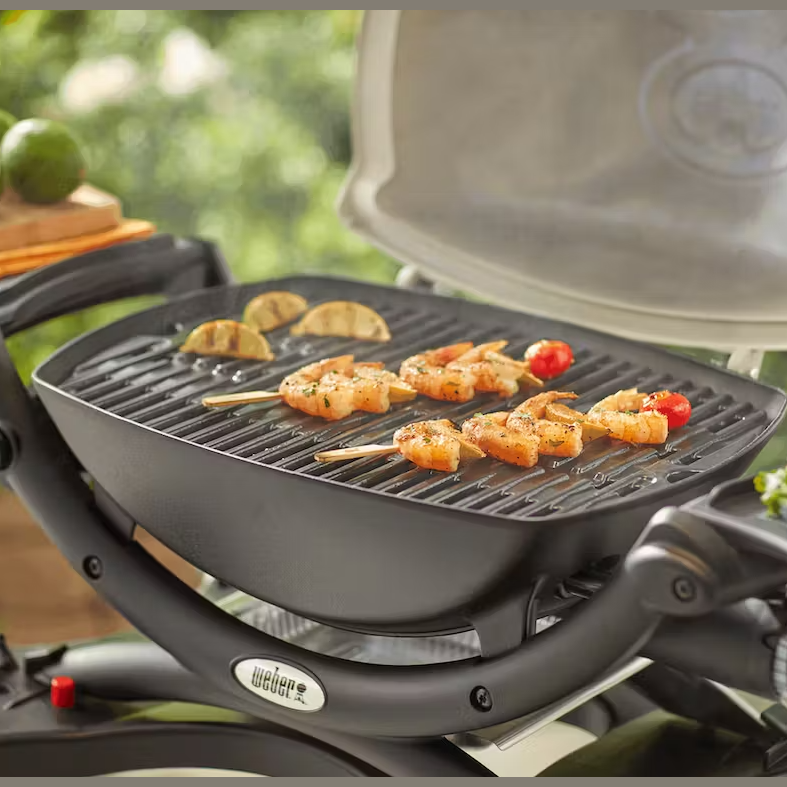 Cast iron cooking grates on Weber grill with shrimp skewers and lime wedges in outdoor living setting