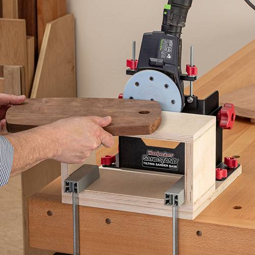 Wooden workpiece being held against a tilting sander base with adjustment knobs for home improvement tools