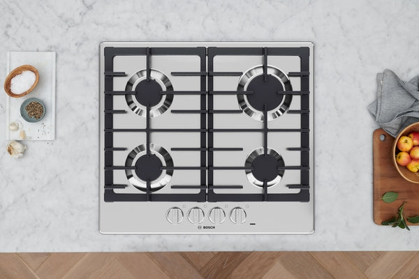 Stainless steel cooktop with four high-efficiency burners and heavy-duty cast iron grates in modern kitchen setup