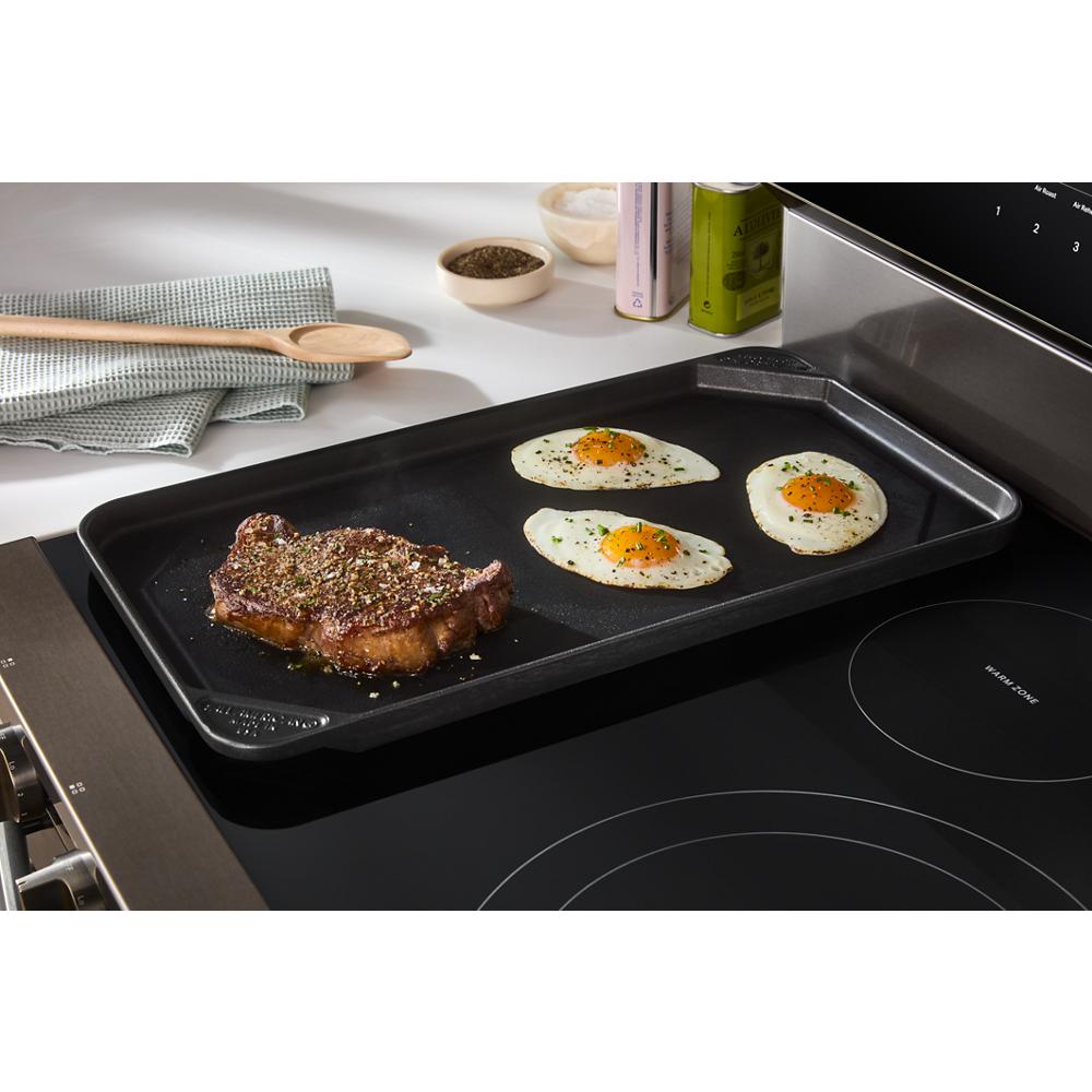 Cooking griddle on black smooth top electric range with steak and three sunny side up eggs from Ranges collection