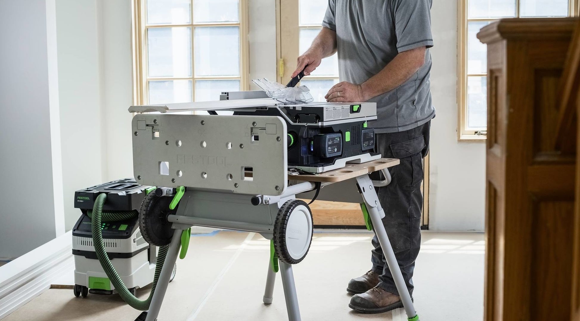 Cordless table saw setup on portable stand with dust extractor, part of electric power tools for home improvement.