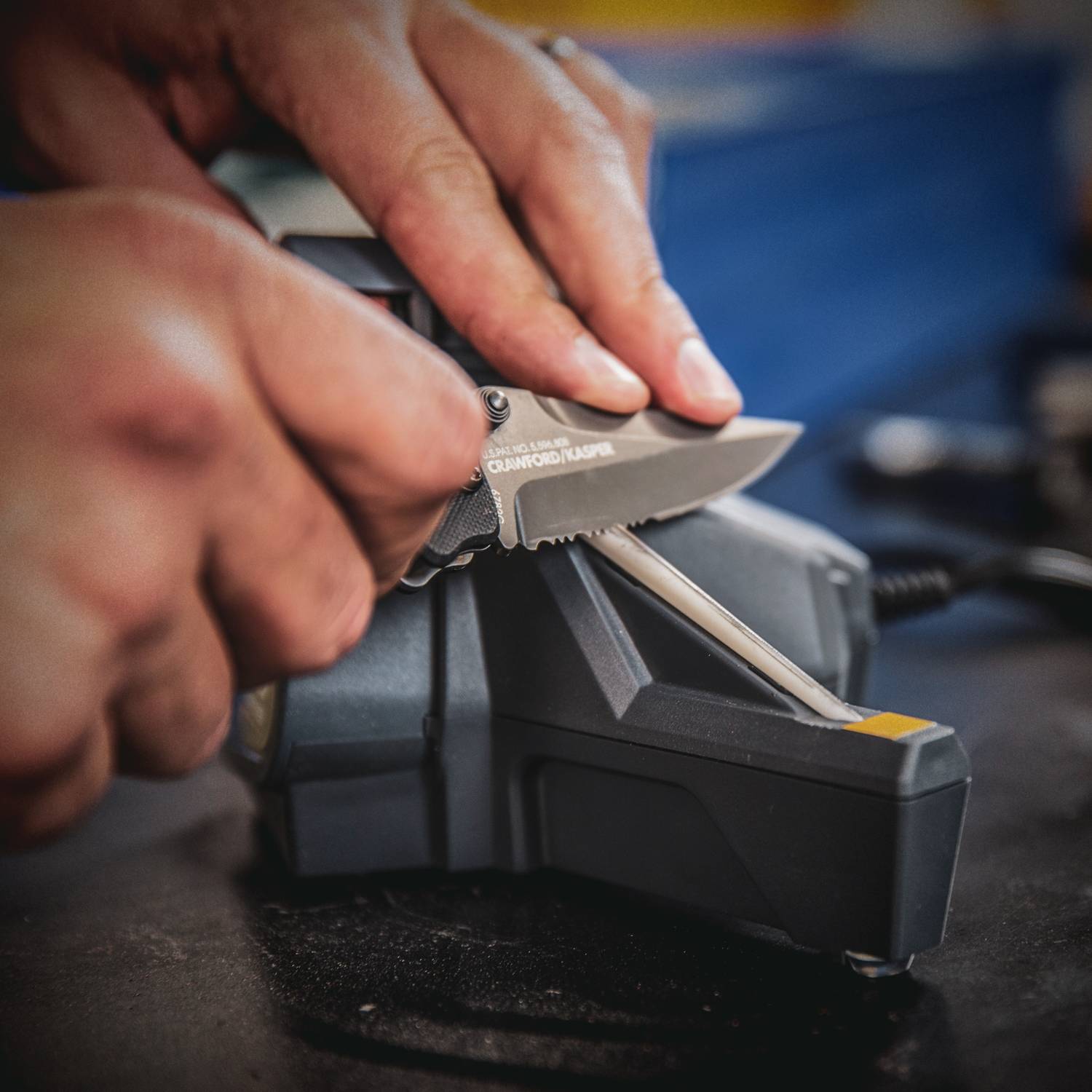 Hands sharpening a serrated knife using a compact black and gray sharpener from woodworking tools collection