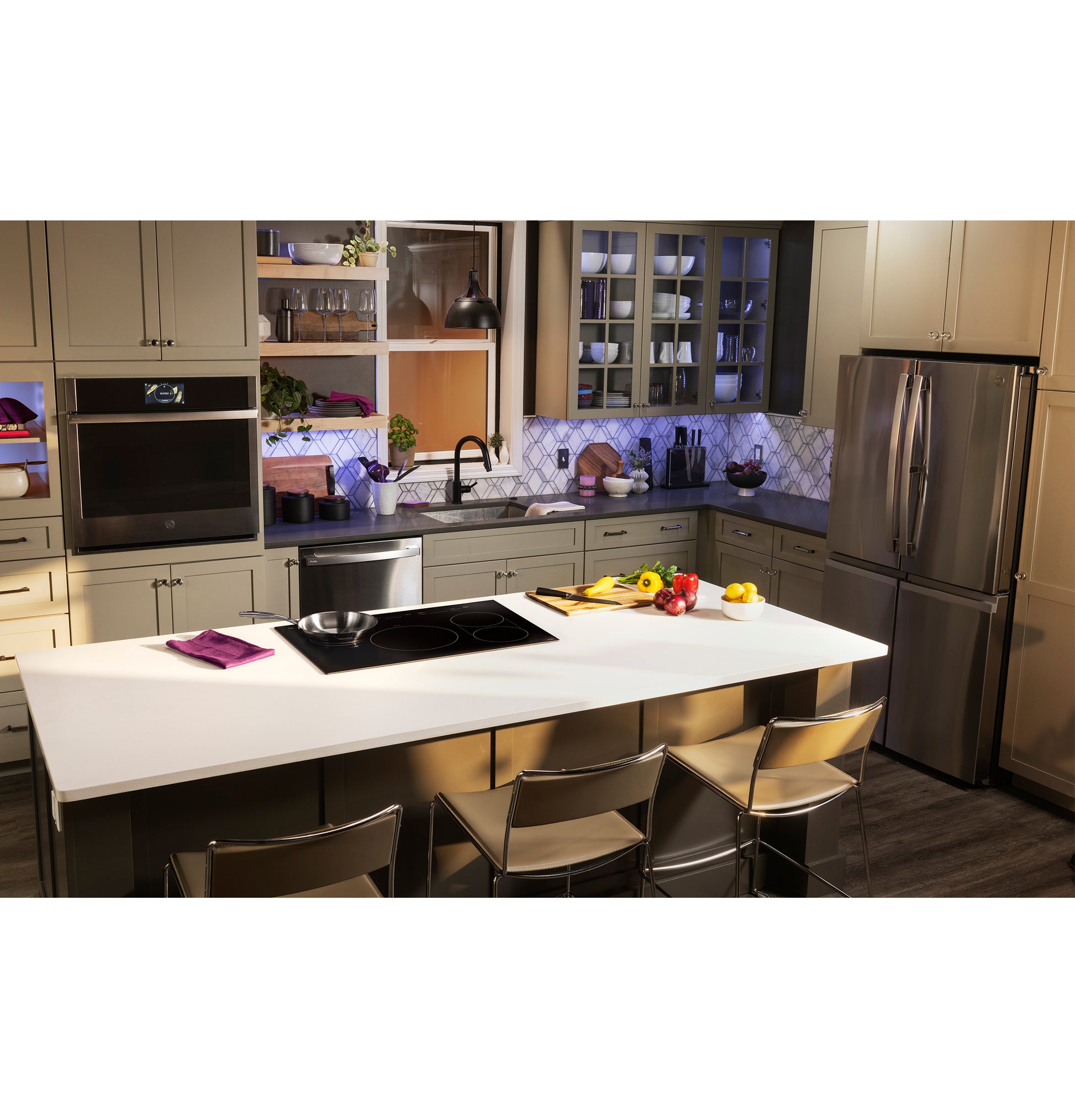 Modern kitchen with white island featuring black built-in induction cooktop and stainless steel appliances nearby