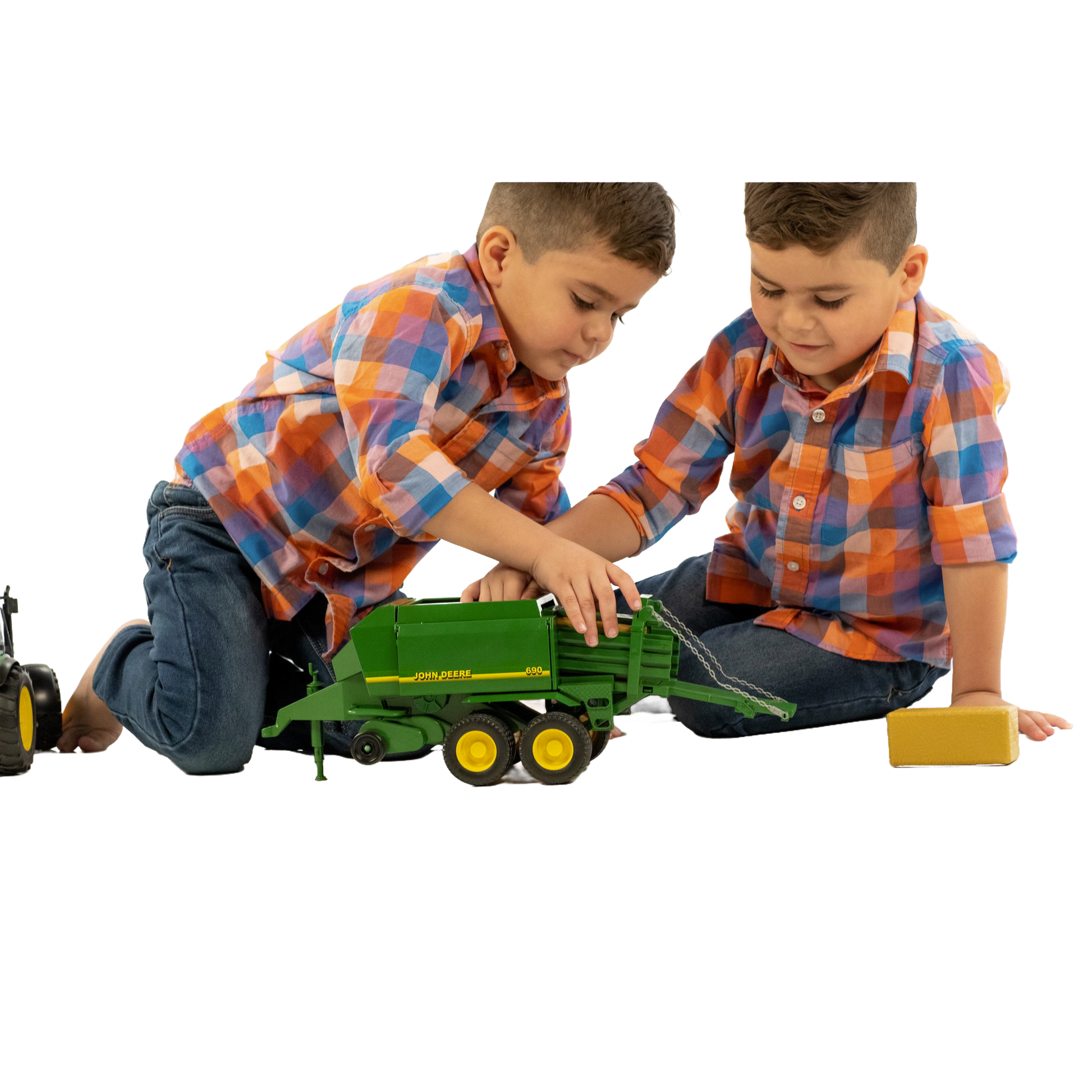Two boys in matching shirts playing with a green toy bale press from Bruder Toys under $100 collection