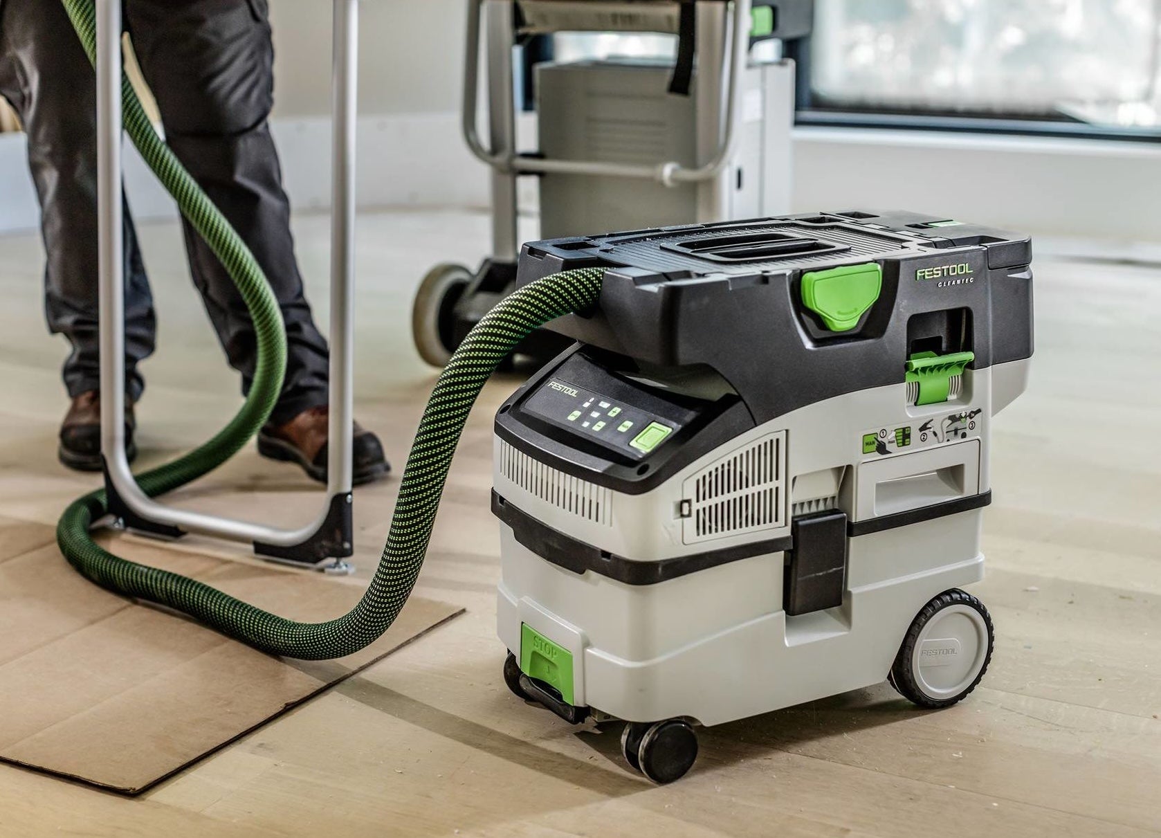 Compact cordless mobile dust extractor with HEPA filtration and hose attached, designed for woodworking and home improvement tasks