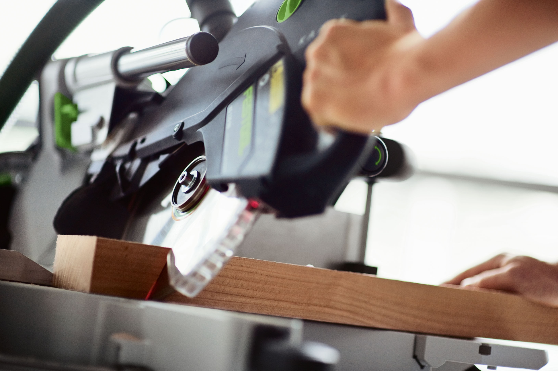 Person guiding Festool sliding compound miter saw for precise wood cutting in power tools and home improvement collection