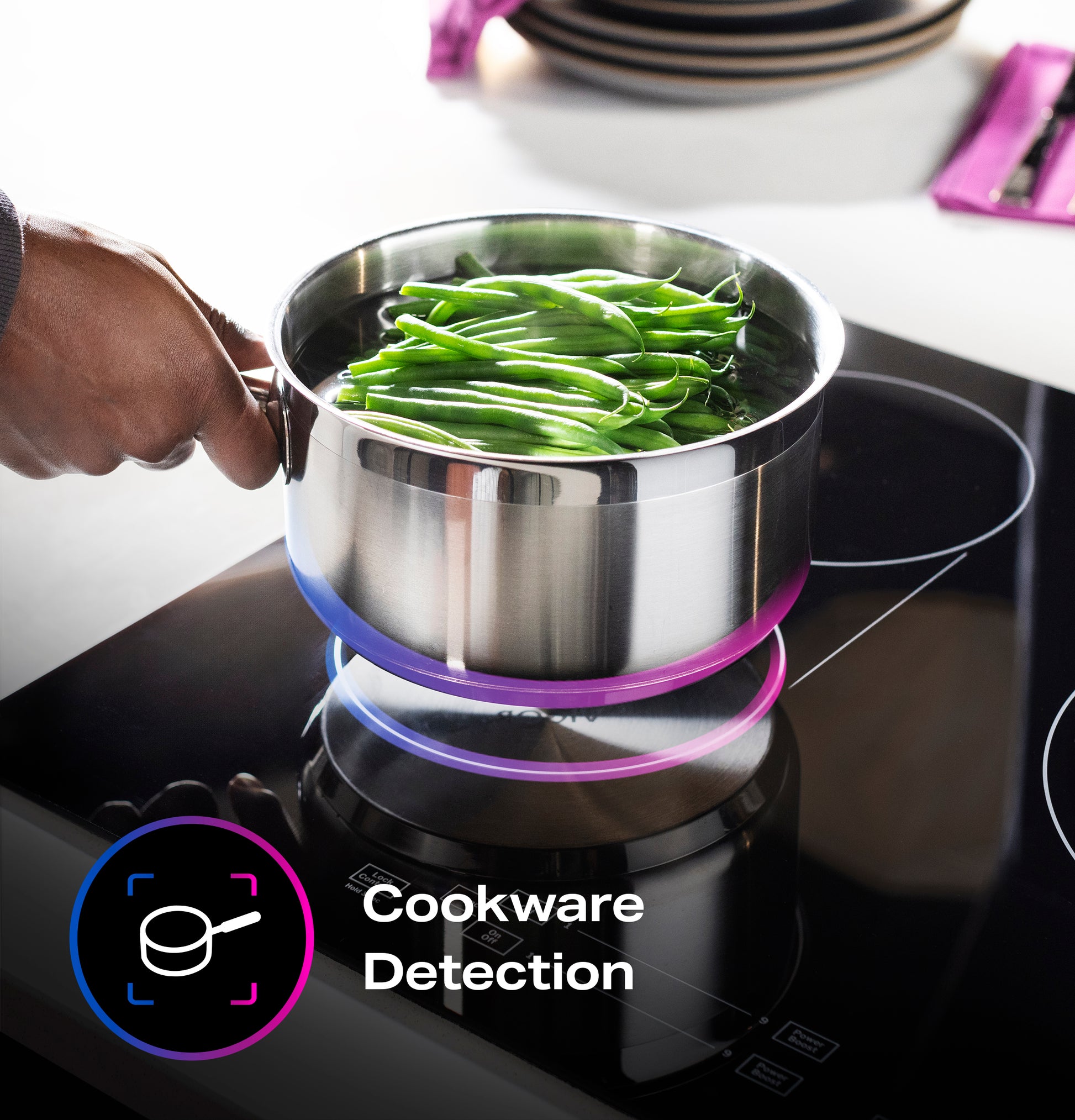Stainless steel pot with green beans boiling on a black touch control induction cooktop for kitchen appliances