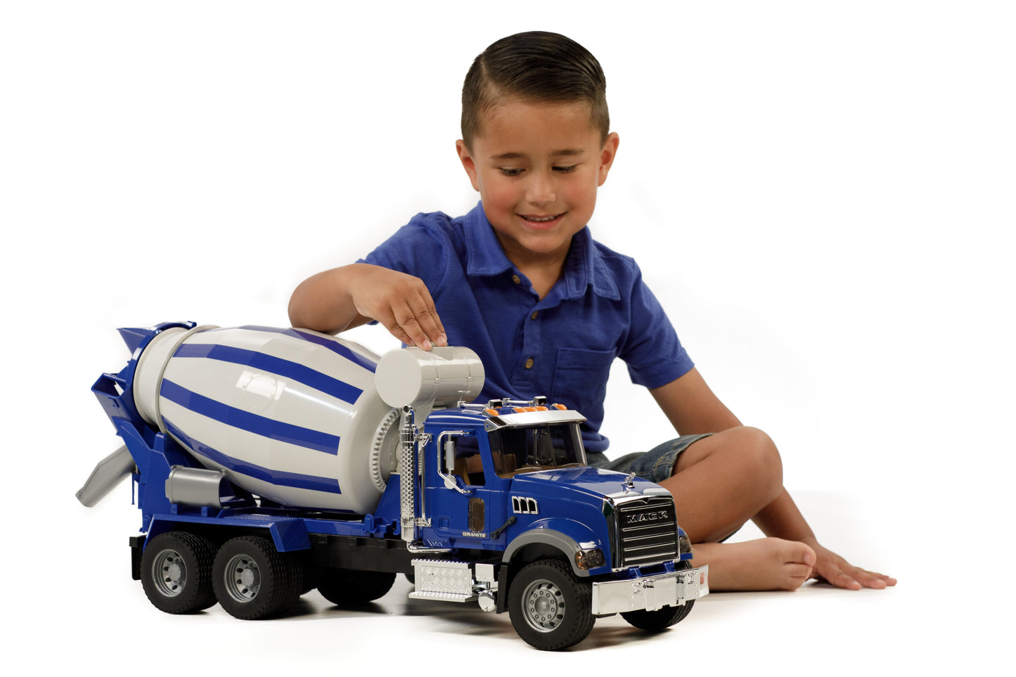Child playing with blue and white 1:16 scale Mack Granite cement mixer truck with rotating drum and detailed cab