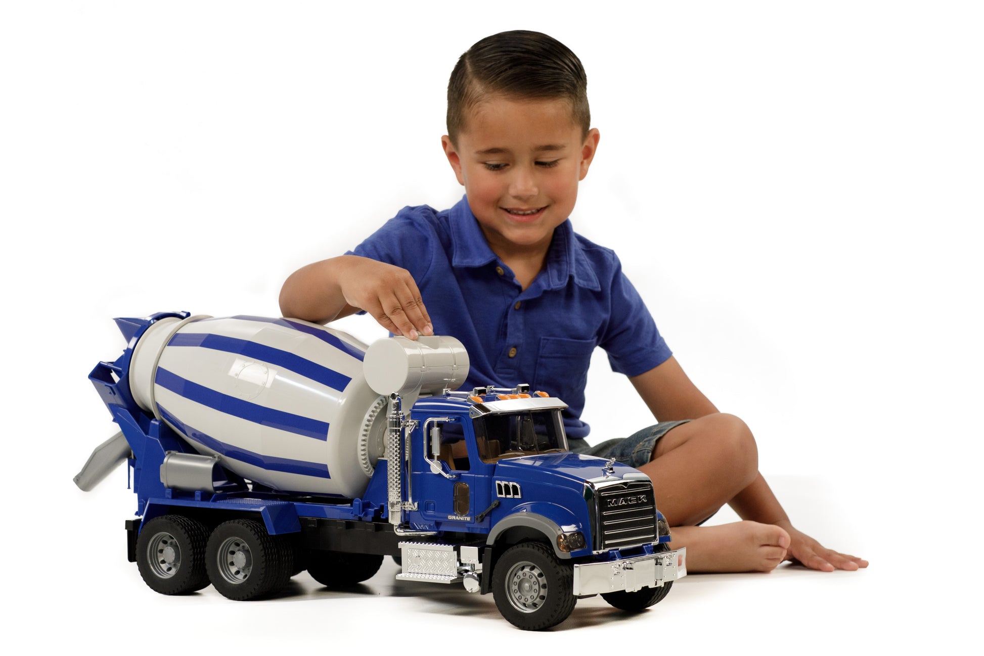 Child playing with blue and white 1:16 scale Mack Granite cement mixer truck with rotating drum and detailed cab