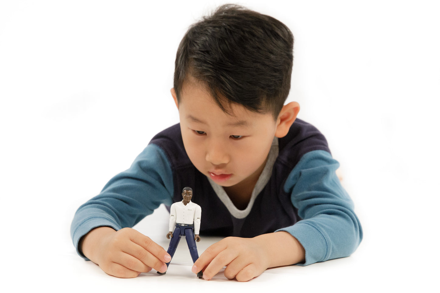 Young boy engaging with a dark-skinned articulated figure wearing a white shirt and dark blue jeans for imaginative play
